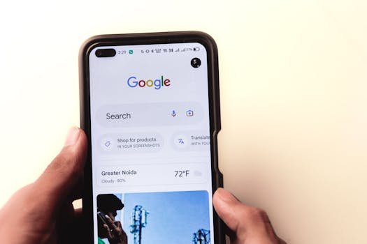 A close-up of a hand holding a smartphone with Google search displayed on the screen.